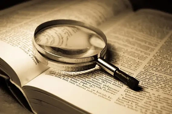 Open dictionary with magnifying glass resting on it