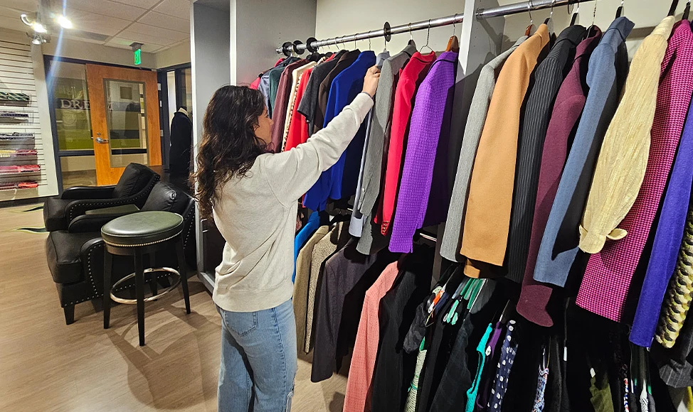 A person searches through clothes on a rack