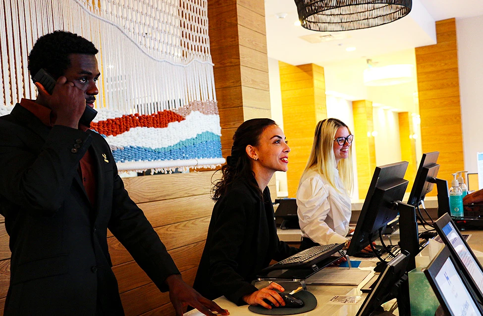 People sit behind a desk with computers