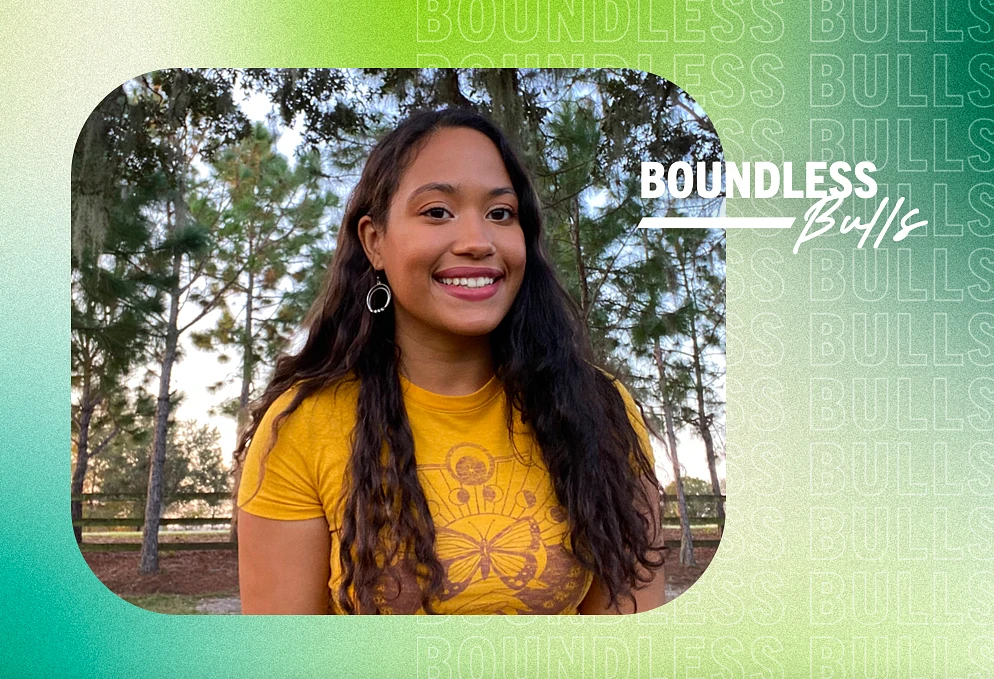 A woman smiles for the camera in front of trees